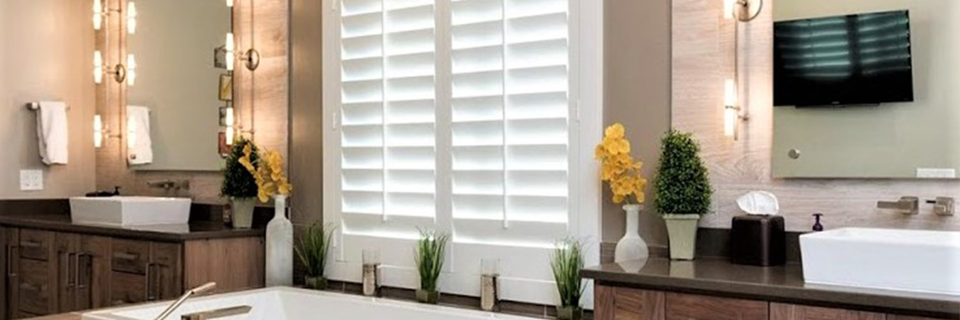 White Polywood shutters above a tub inside a large modern bathroom