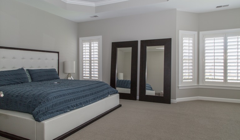 Polywood plantation shutters work well with minimalist design. White shutters in a minimalist bedroom in Boston.